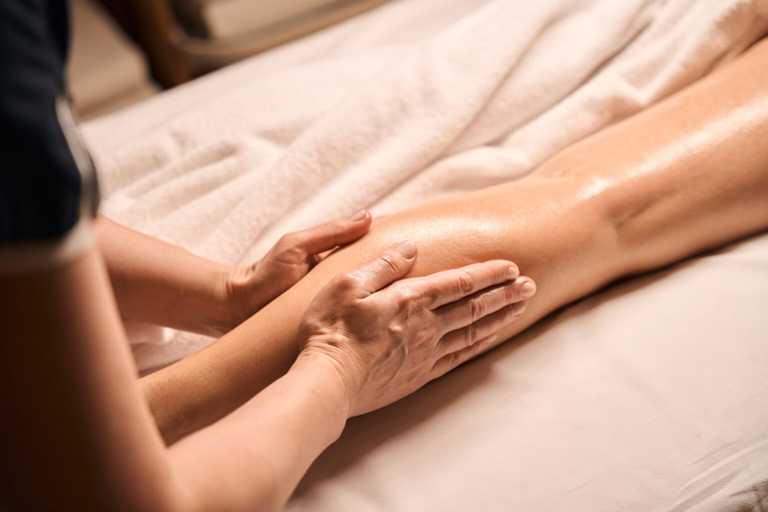 Ein Therapeut der Physiotherapie Hennecke & Hennecke führt eine sanfte Manuelle Lymphdrainage (MLD) am Unterschenkel durch, um Schwellungen zu lindern und das Gewebe zu entstauen.